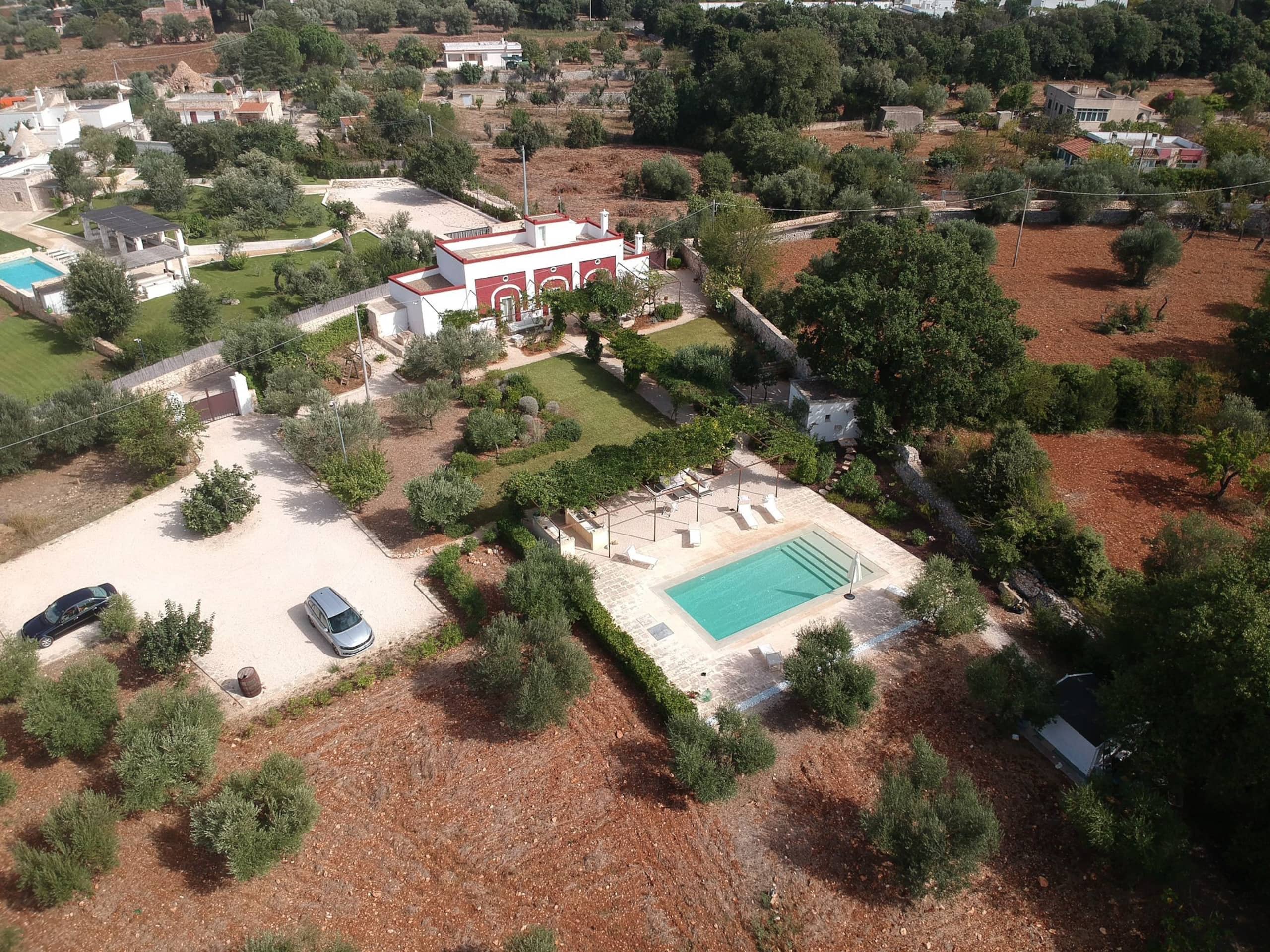 The masseria and its pool seen from above, amid the olive groves of the Polignano countryside